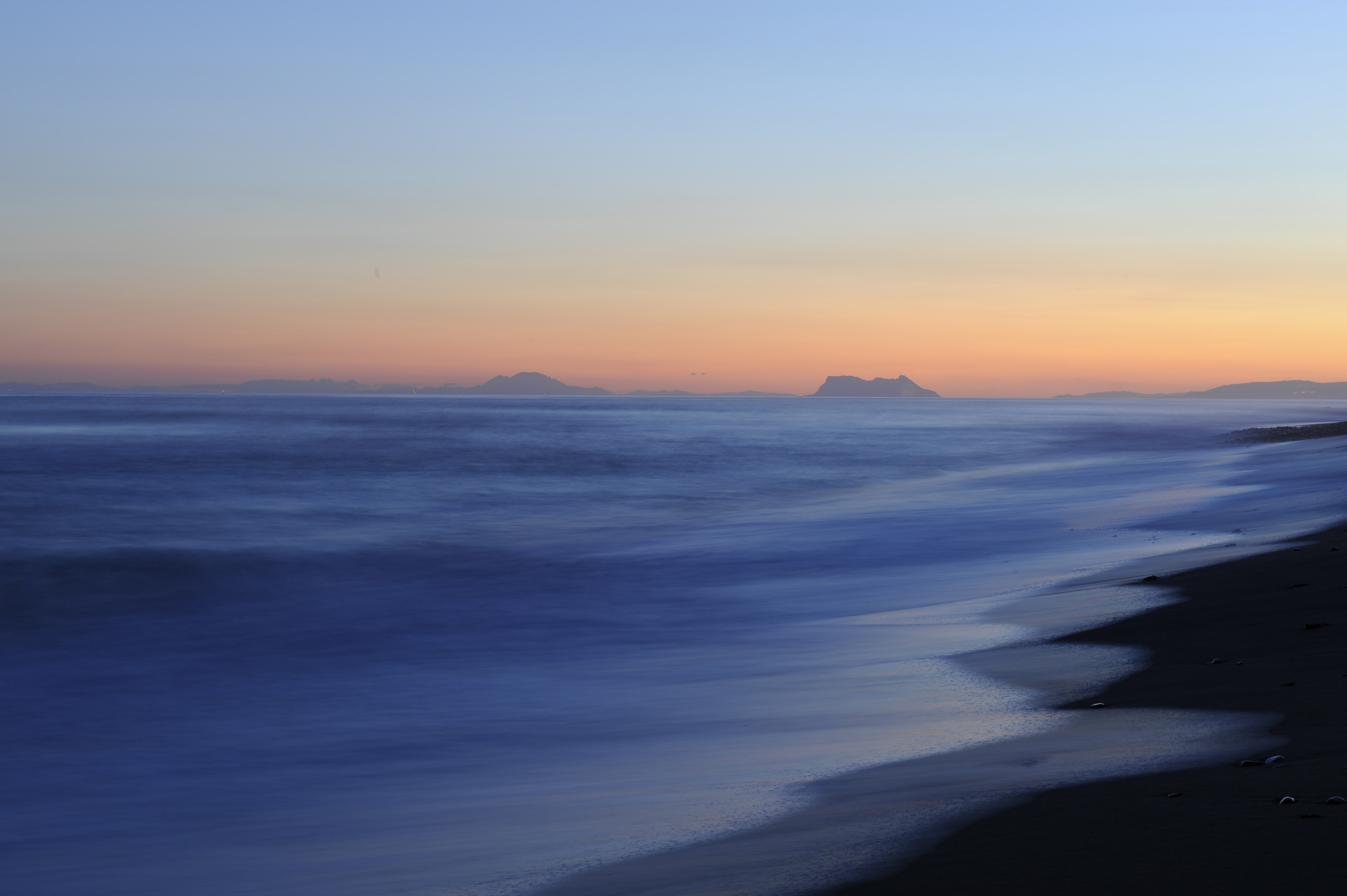 Looking out to the Two Pillars of Hercules on the horizon at sunset, as the sky glows with warm hues © Michelle Chaplow