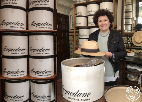 Cristina Vega inside her historic hat shop, Sombrerería Maquedano in Seville, with towers of vintage hatboxes. © Fiona Flores